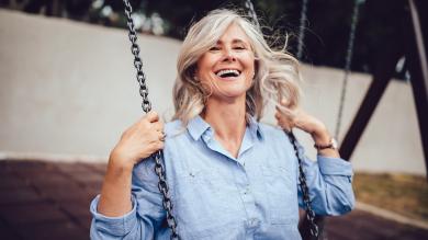 
		Mature woman swings and laughs on the playground
	